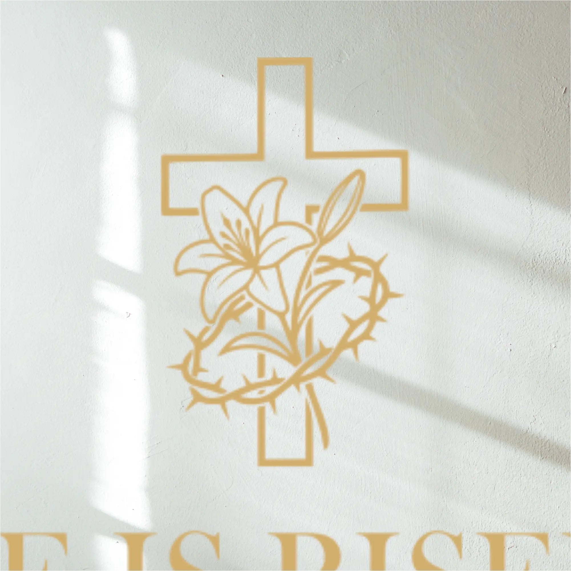 Gold cross with lily and thorns decal design on white wall above a decal  with 'He is Risen' text.