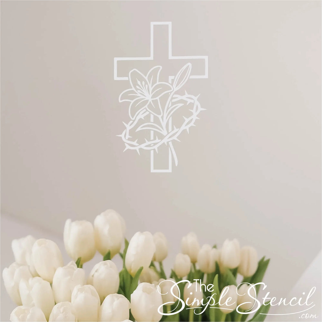 White silhouette wall decal of a Christian cross intertwined with a lily and crown of thorns wall decal, displayed in a modern home office above a desk with plants.