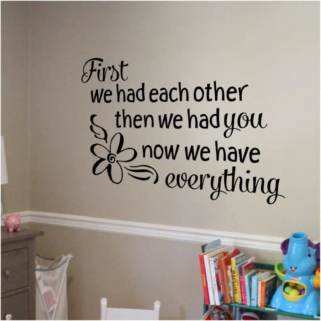 A beautifully designed wall decal for baby girls nursery by The Simple Stencil displayed on baby nursery wall and reads: First we had each other then we had you now we have everything. Includes flower graphic