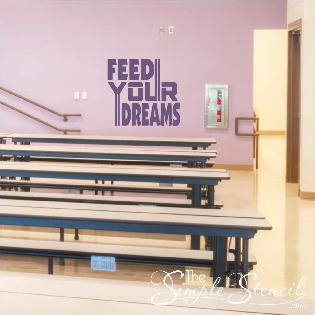 "Feed Your Dreams" wall decal applied on a school cafeteria wall with colorful lunch tables and chairs.