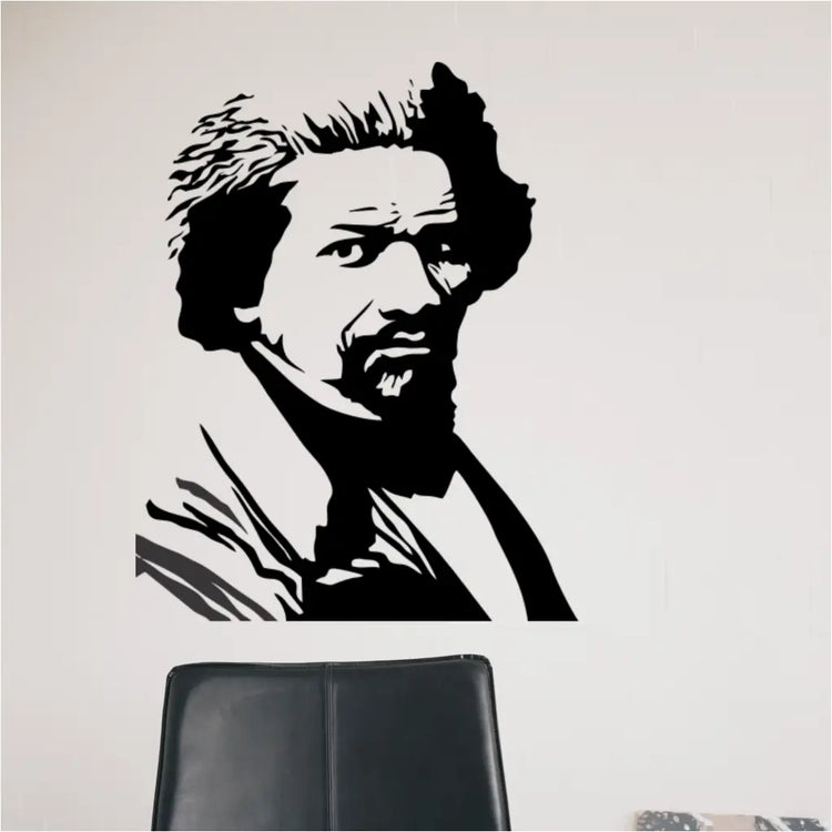 A close-up view of the Frederick Douglass silhouette decal applied to a white wall, showing the detail of the vinyl graphic above a black office chair.