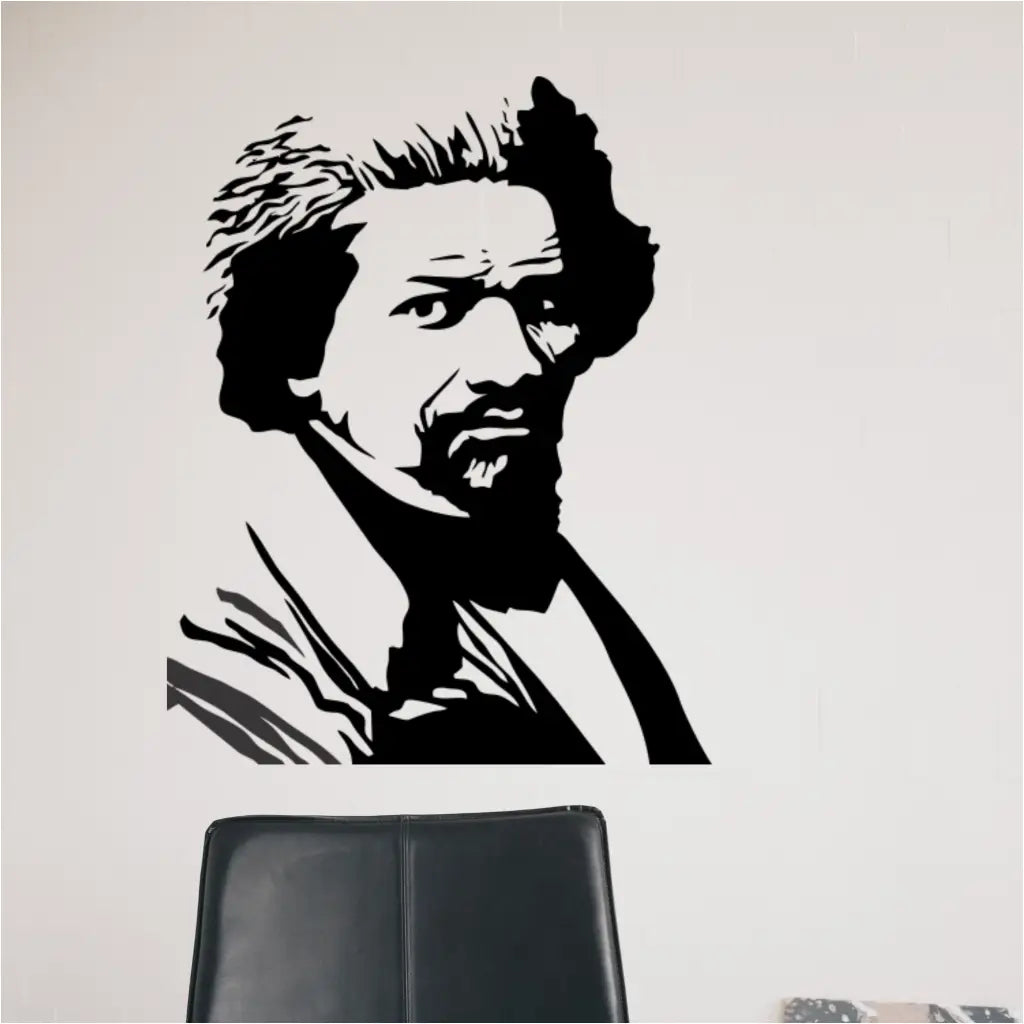 A close-up view of the Frederick Douglass silhouette decal applied to a white wall, showing the detail of the vinyl graphic above a black office chair.