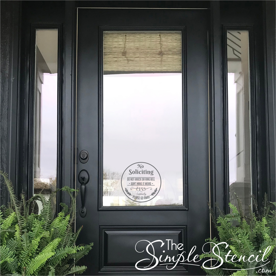 Round no soliciting window decal on the glass of a black front door with sidelight windows