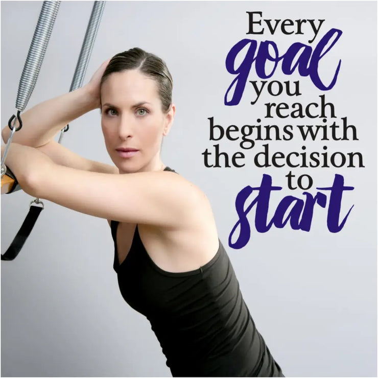 A black and blue wall decal displayed on a gym wall with a pretty girl in workout gear. Quote reads: Every goal you reach begins with the decision to start.