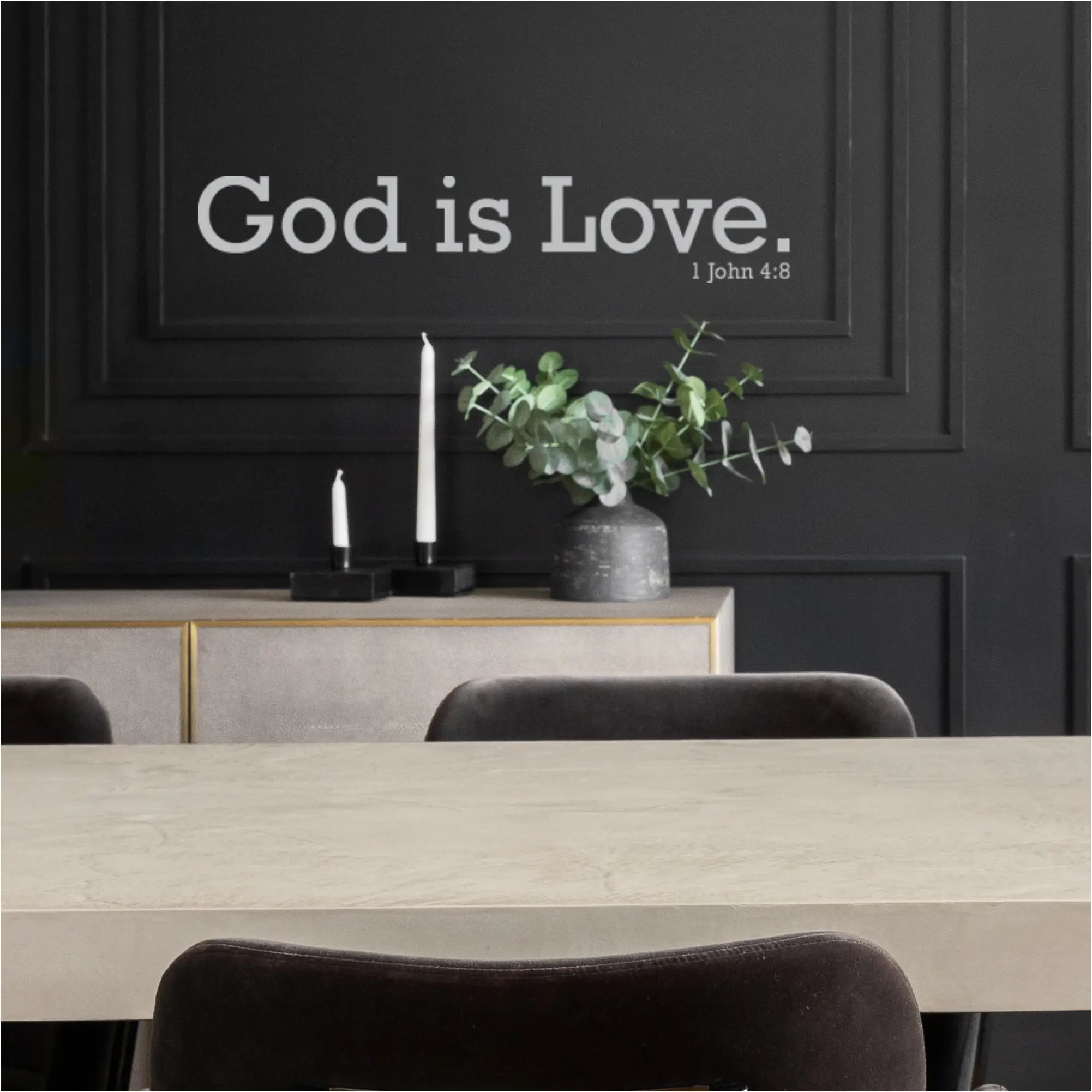 Close-up of a white "God is Love 1 John 4:8" wall decal applied to a dark gray wall in a modern church hall
