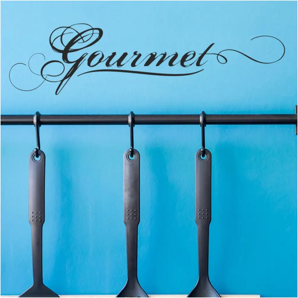 Small "gourmet" wall decal by The Simple Stencil shown installed over hanging kitchen utensils to dress up a boring kitchen wall.