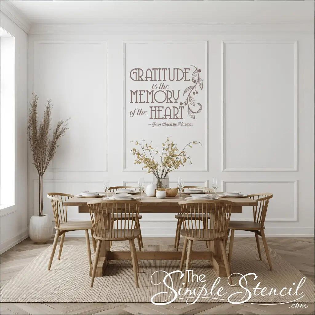 The elegant French quote decal, "Gratitude is the Memory of the Heart," in a light brown color, displayed in a formal dining room with a wooden table and white wainscoting.