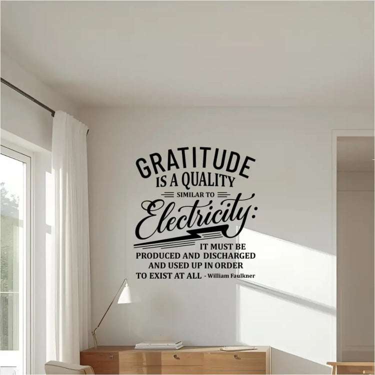 A black wall decal of the quote "Gratitude is a quality similar to electricity..." by William Faulkner, installed on a white wall above a wooden credenza in a home or office.
