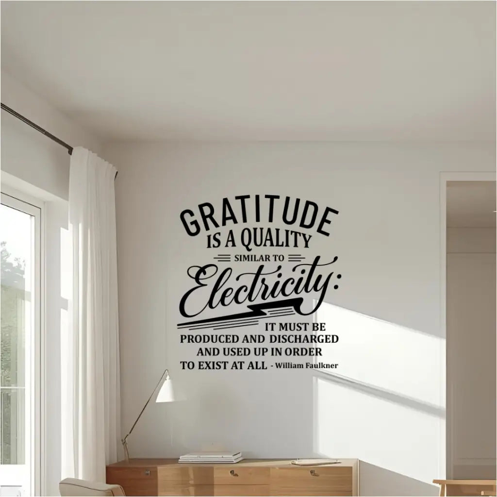 A black wall decal of the quote "Gratitude is a quality similar to electricity..." by William Faulkner, installed on a white wall above a wooden credenza in a home or office.