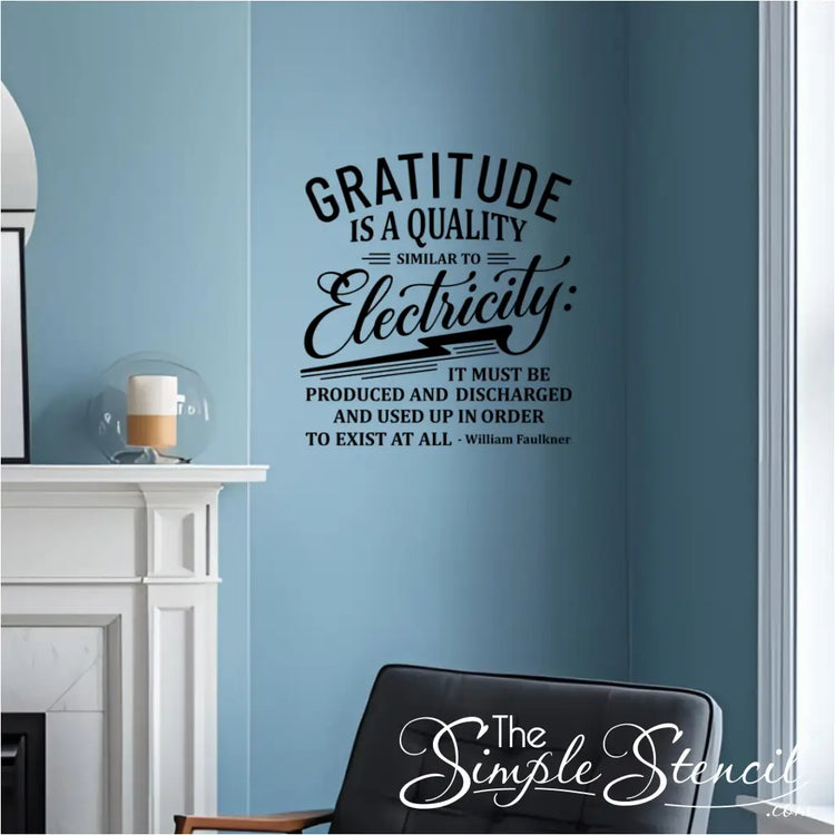 A black wall decal of the quote "Gratitude is a quality similar to electricity..." by William Faulkner, installed on a light blue wall above a fireplace in a cozy living room.