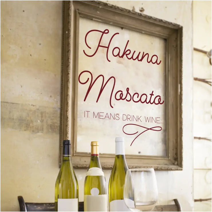 Hakuna Mascato It Means Drink Wine with flourish wall decal shown on a wall surrounded by a picture frame only.