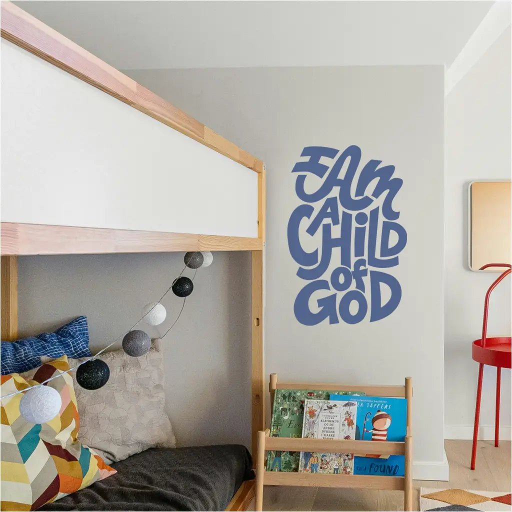 The phrase "I am a child of god" wall decal in navy blue displayed as a wall decal in a cozy child's room / play room