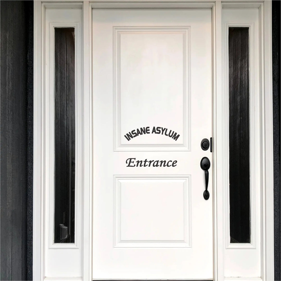 A black "Insane Asylum Entrance" vinyl decal on a white front door, positioned to look like a welcome sign.