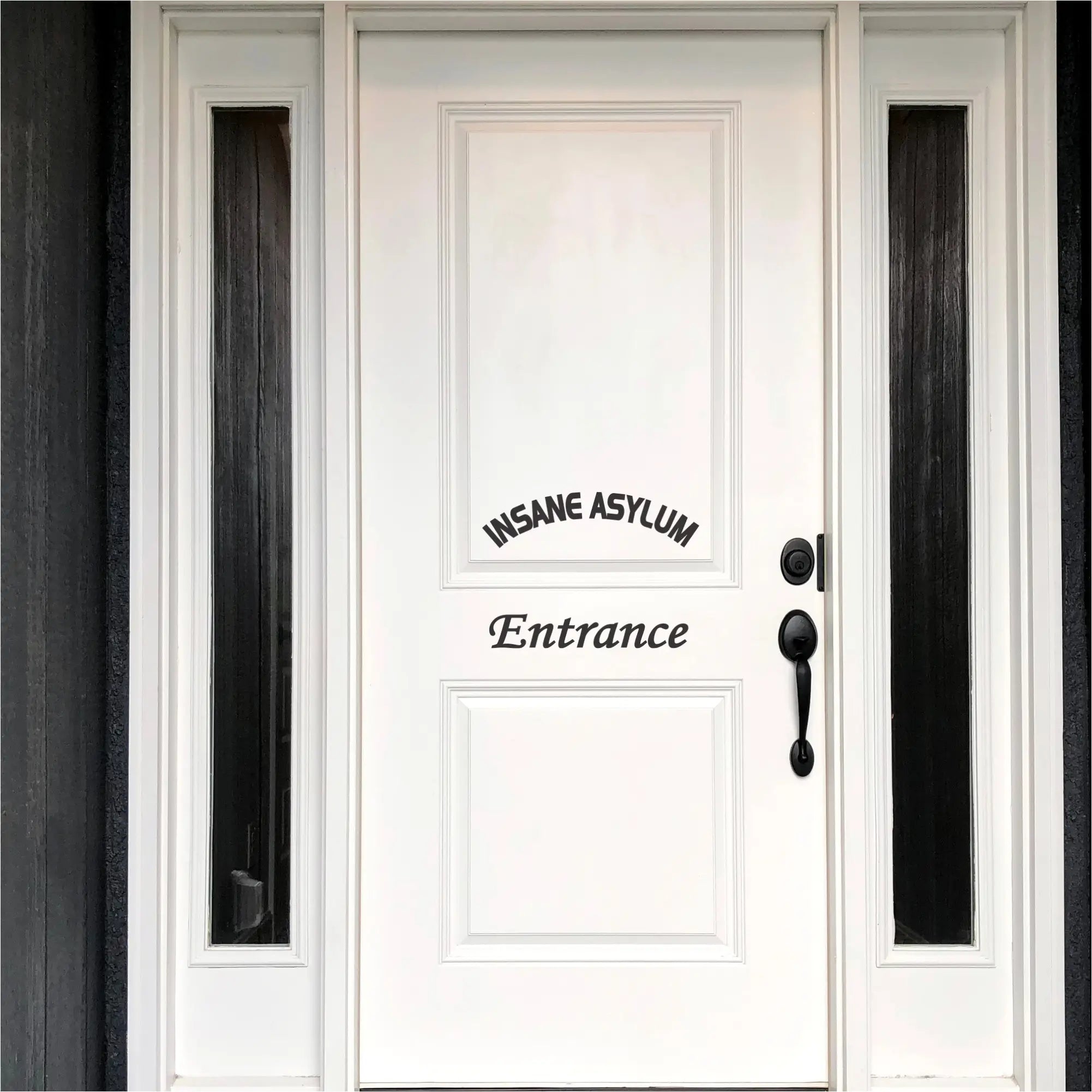 A black "Insane Asylum Entrance" vinyl decal on a white front door, positioned to look like a welcome sign.