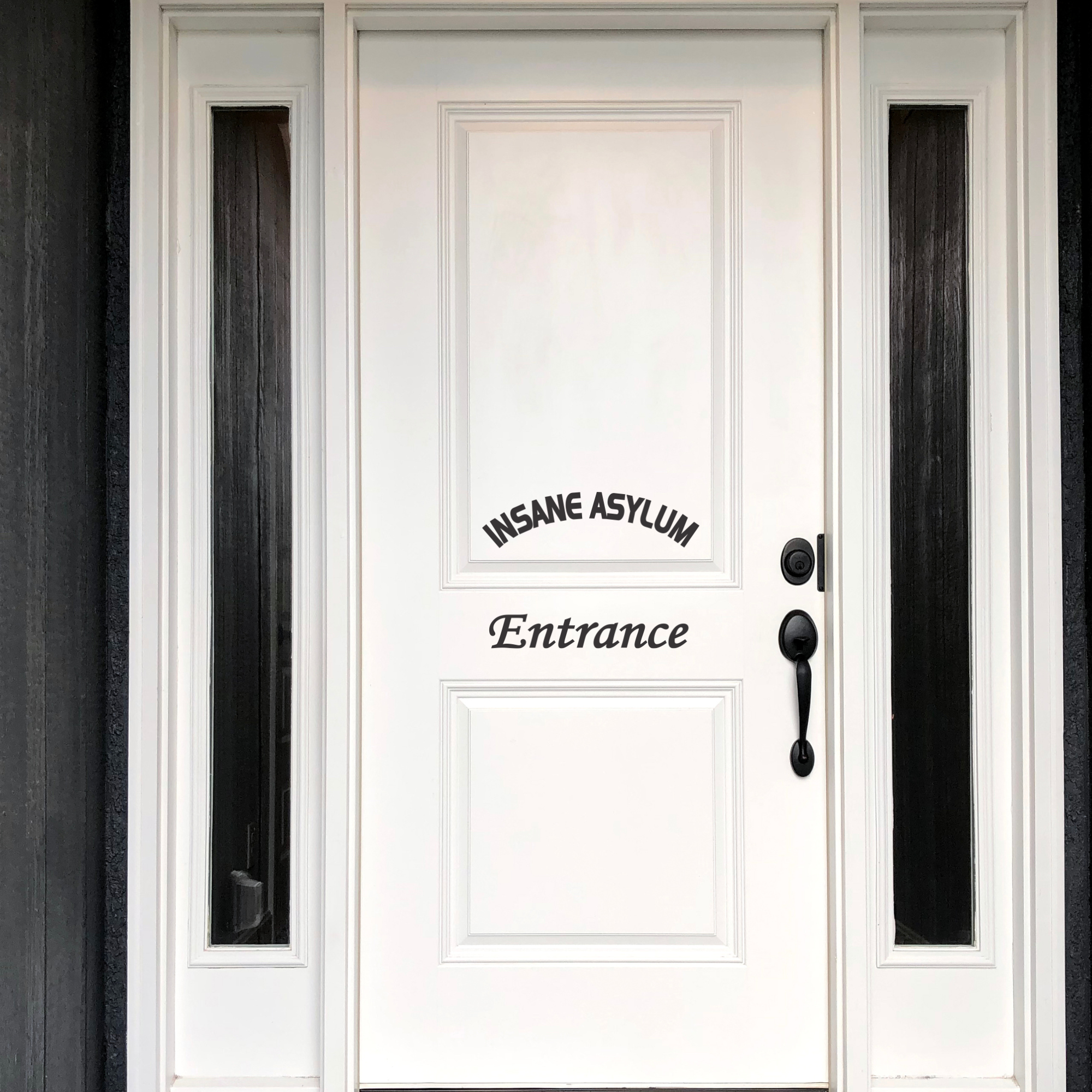 A black "Insane Asylum Entrance" vinyl decal on a white front door, positioned to look like a welcome sign.