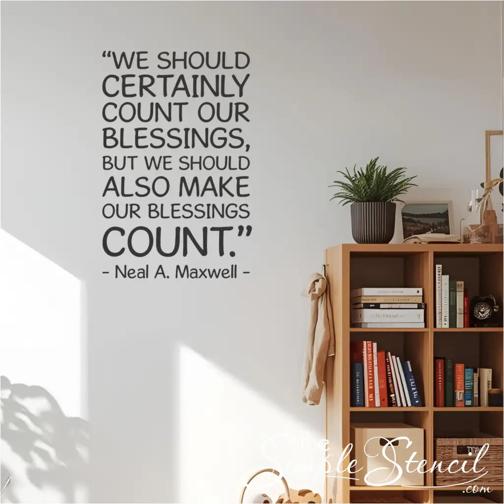 The "Make Our Blessings Count" inspirational quote decal on a wall next to a wooden bookshelf in a sunlit home office.