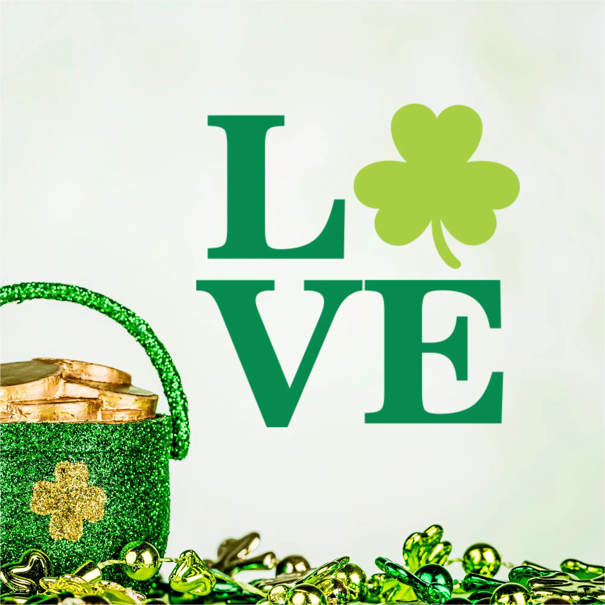 Green 'LOVE' vinyl lettering featuring a clover accent, paired with a sparkling green pot of gold and lucky gold coins for St. Patrick's Day party inspiration.