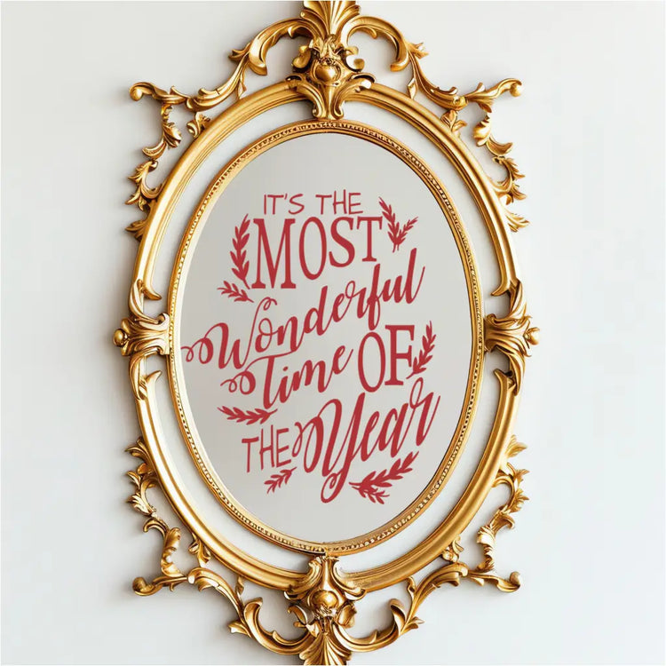 Red Christmas song lyrics vinyl decal on an ornate gold mirror reading 'It's the Most Wonderful Time of the Year.' This holiday mirror sticker features a whimsical scripted font and is perfect for holiday party decor and retail window displays.