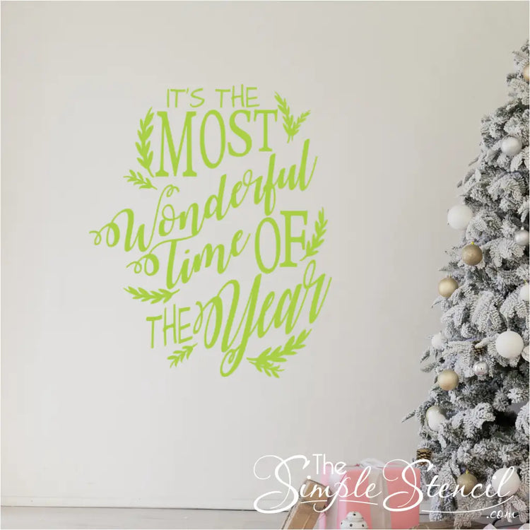 Large key lime green "Most Wonderful Time of the Year" vinyl lettering on a white wall next to a flocked Christmas tree and gifts. The festive vinyl graphic has delicate branch flourishes and is great for family room, office or even store front window decorating.
