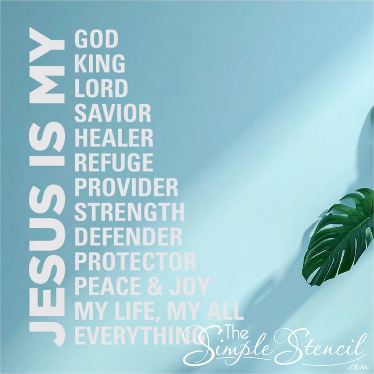 Large Christian wall decal titled 'Jesus Is My Everything' listing the names of God, styled in a contemporary living room on a blue wall next to a window and plant.