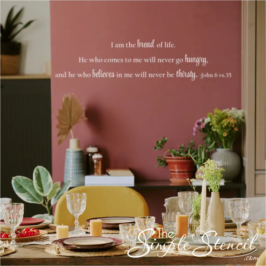 Horizontal vinyl decal of John 6:35 installed on a deep red wall above a decorated dinner party table, highlighting the decal as spiritual dining room wall art.