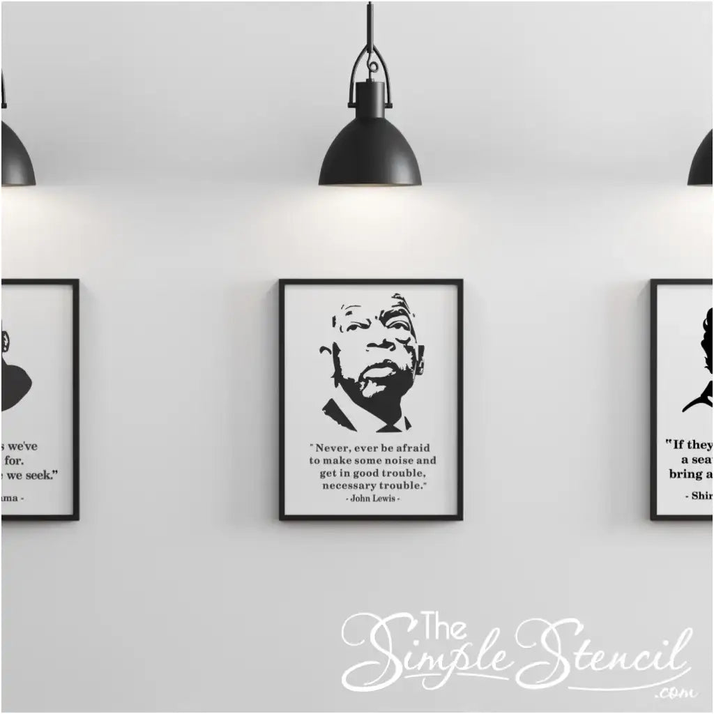 Gallery wall display featuring three framed prints under pendant lighting, with the center poster showcasing the John Lewis silhouette and full "Good Trouble" quote.