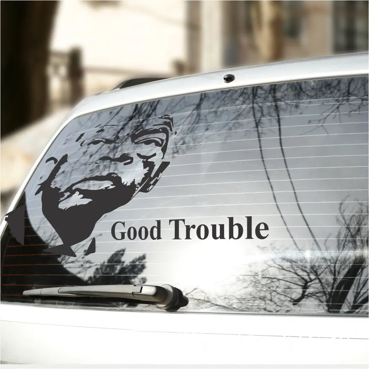 John Lewis silhouette portrait and the phrase "Good Trouble" vinyl decal applied to the rear window of a vehicle, demonstrating outdoor durability.