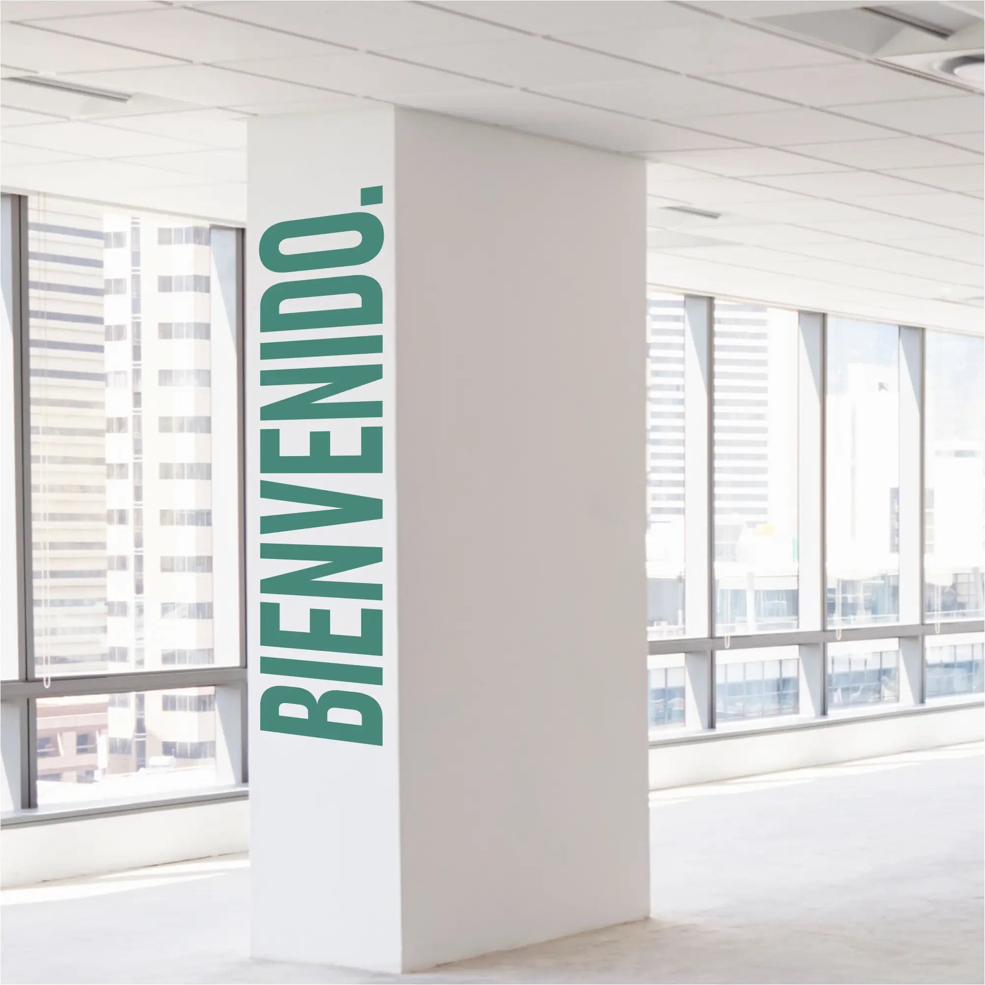 A white pillar featuring a large modern bienvenido wall decal with bold green vertical lettering to welcome guests