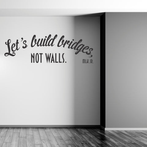 Large wall decal display in black of the words by Martin Luther King Jr. that read: Let's build bridges, not walls.