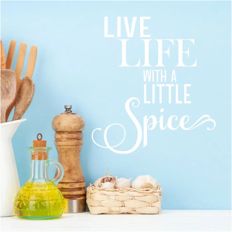 An adorable white decal by The Simple Stencil displayed on a pantry wall that reads "Live life with a little spice" in a pretty style. Perfect for the interior side of a spice cabinet