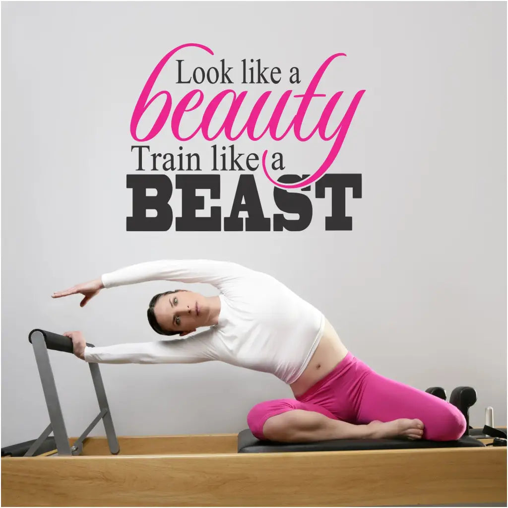 Large two color wall decal displayed on a women's gym wall reads: Look like a beauty, train like a beast by The Simple Stencil
