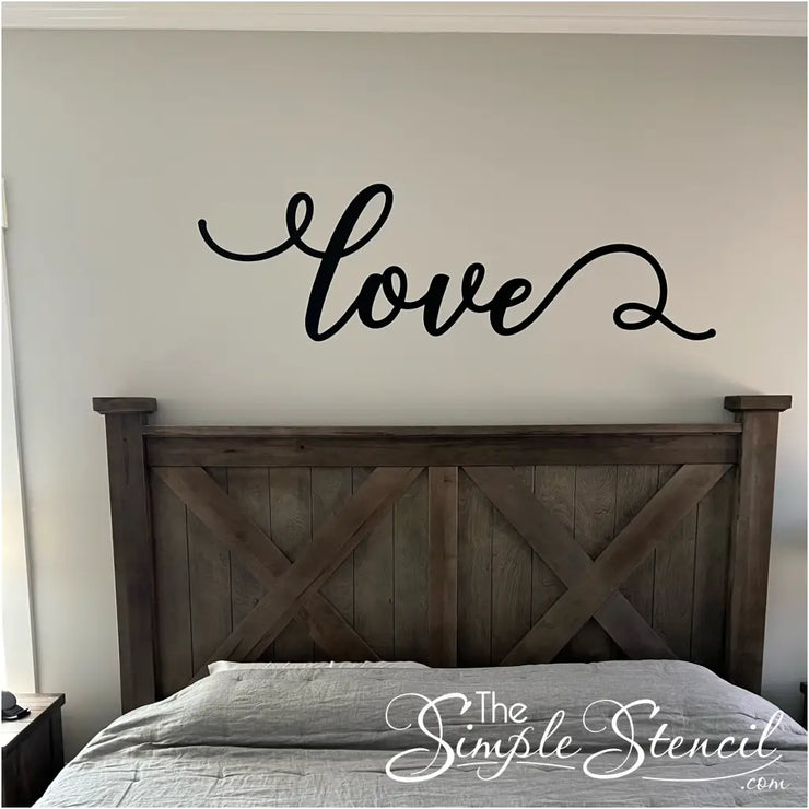 Romantic "Love" scripted decal wall art picture from a happy customer, Chris B. This is shown in black behind a master bedroom headboard perfectly sized by The Simple Stencil. 