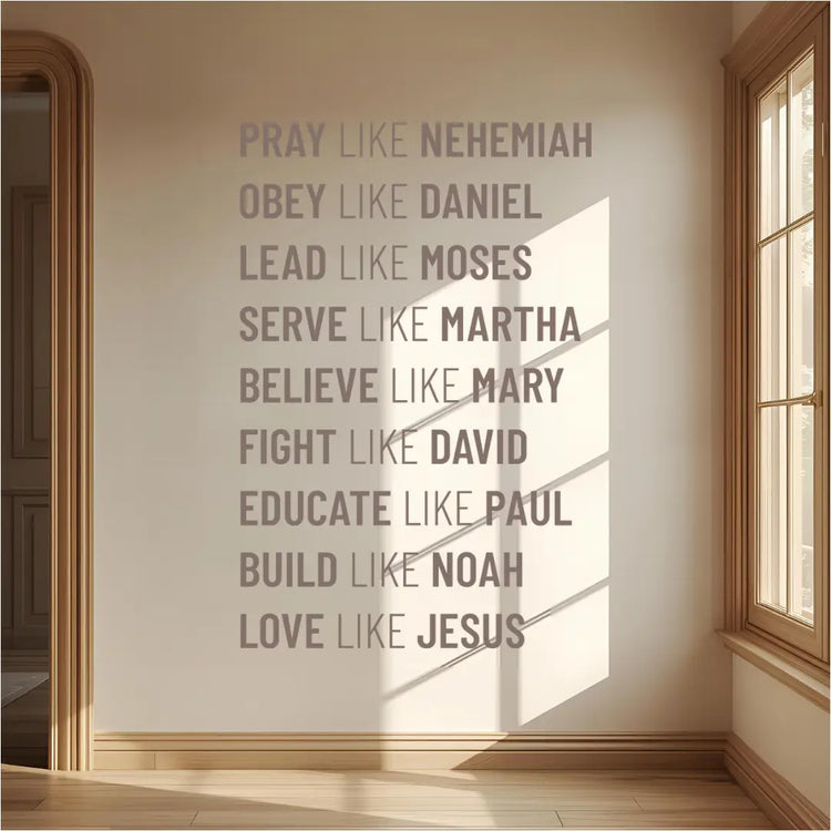 A gray wall decal listing nine biblical virtues and figures, starting with "PRAY LIKE NEHEMIAH," installed on a light beige wall in a sunlit hallway with a wooden floor and a large window.