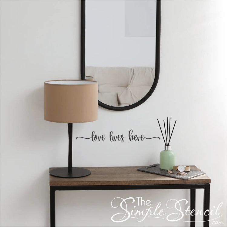 Black vinyl 'Love Lives Here' decal applied to a light-colored entryway wall.