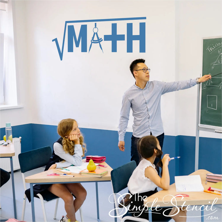 A blue math-themed wall sticker featuring a square root and compass design applied to a white and blue classroom wall. An Asian male teacher points to a chalkboard while students sit at their desks, highlighting the decal as perfect decorative inspiration for STEM-focused classrooms.