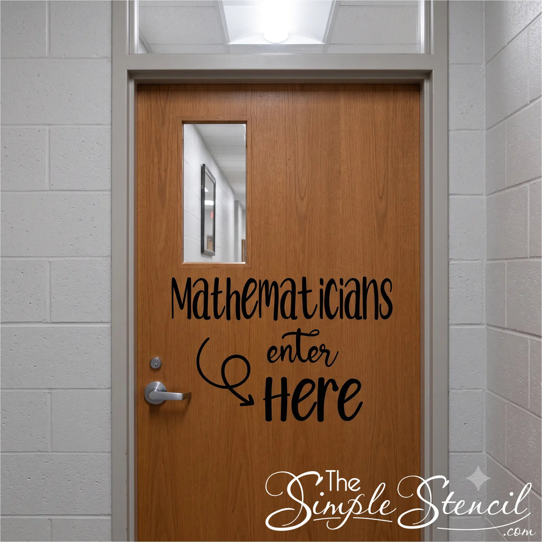 A black typography vinyl decal applied to a wooden classroom door in a school hallway. The decal reads 'Mathematicians Enter Here' with a swirling arrow, and hints of a math classroom with whiteboards and equations are visible through the slightly ajar door.