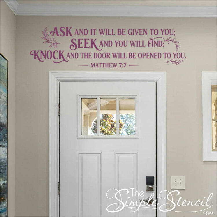 Welcoming wall quotes for church lobby or home entrance displaying Matthew 7:7 in a sophisticated eggplant purple vinyl transfer centered beautifully over a white multi-panel interior door.