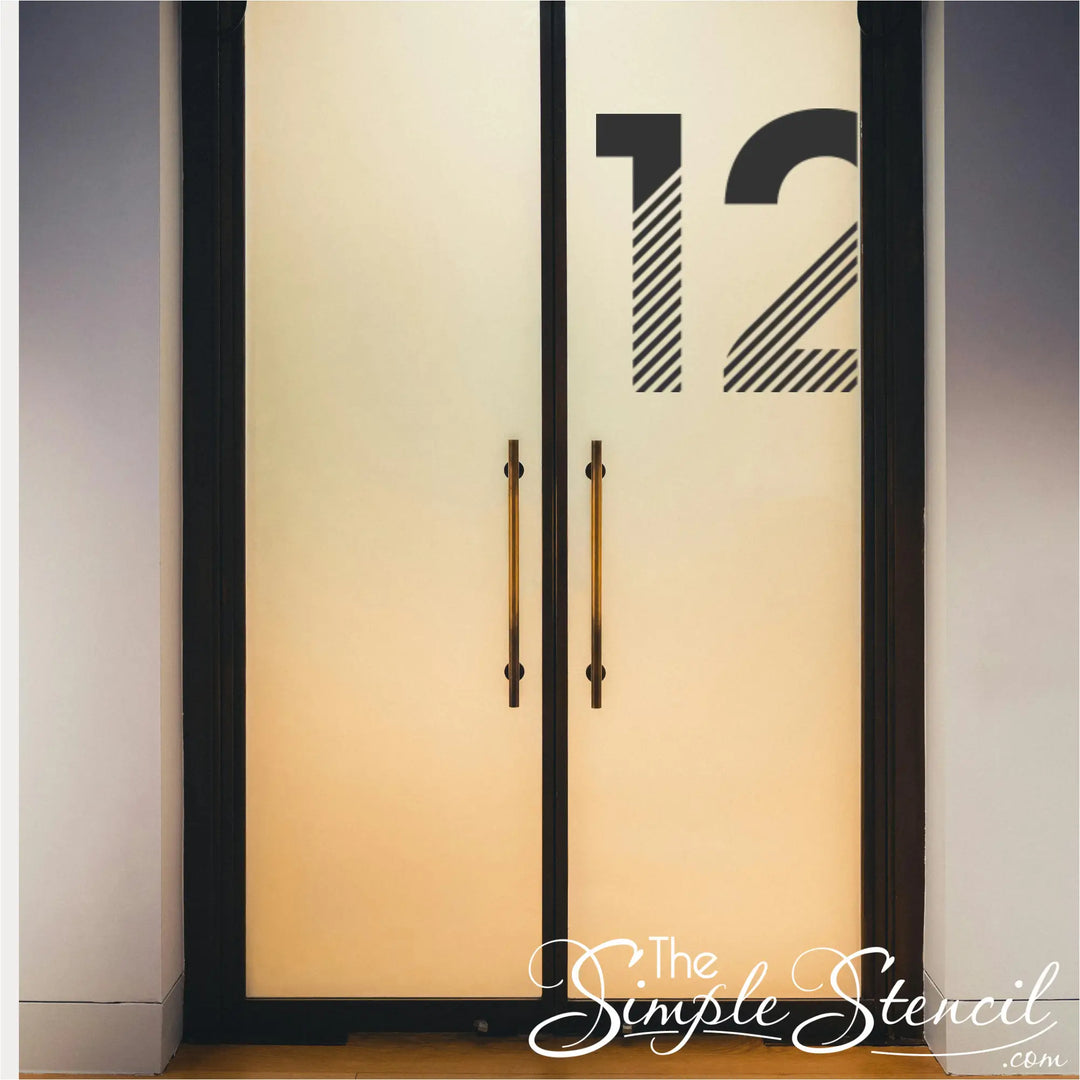 Number 12 decal in black vinyl applied to the top corner of frosted glass double doors in a high-end commercial lobby.