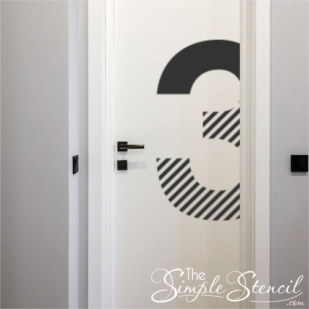 Large black vinyl number 3 applied to a white wooden apartment door with a minimalist black handle.