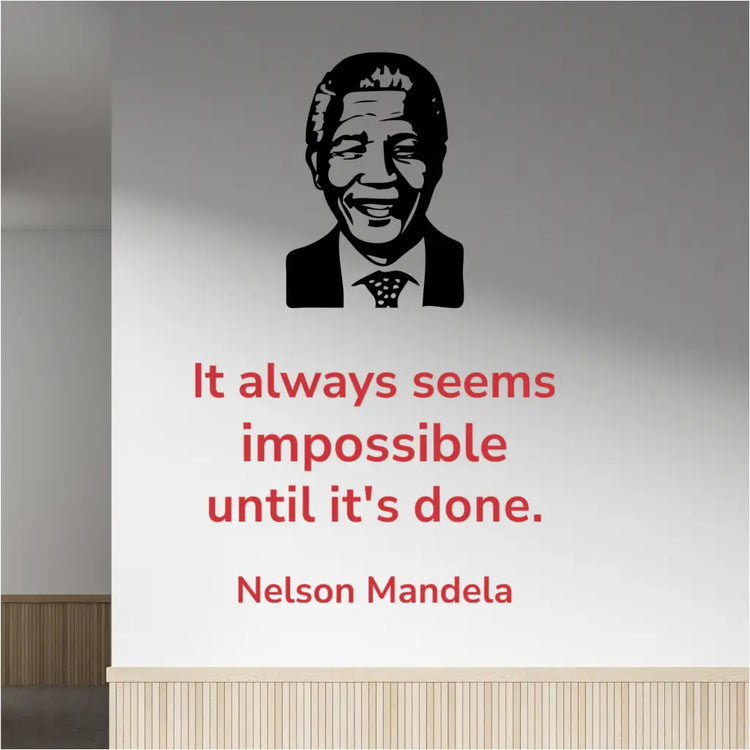 Red Nelson Mandela quote "It always seems impossible until it's done" wall decal in Modern font, placed next to a black silhouette image decal of Nelson Mandela, on a light-colored office hallway wall.