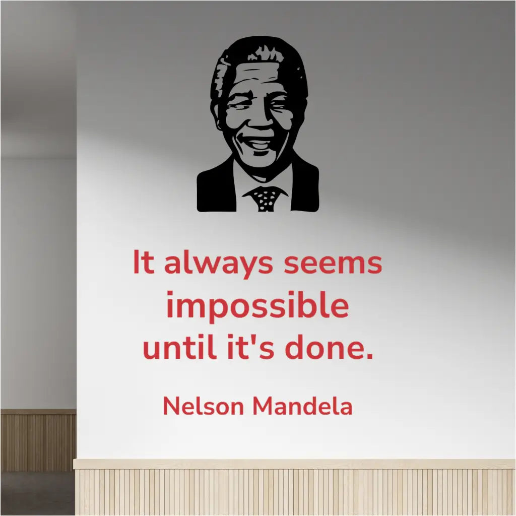 Red Nelson Mandela quote "It always seems impossible until it's done" wall decal in Modern font, placed next to a black silhouette image decal of Nelson Mandela, on a light-colored office hallway wall.