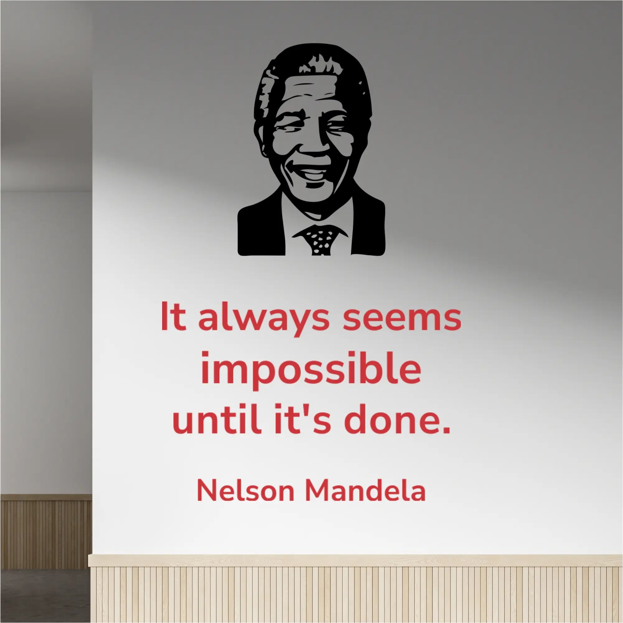 Red Nelson Mandela quote "It always seems impossible until it's done" wall decal in Modern font, placed next to a black silhouette image decal of Nelson Mandela, on a light-colored office hallway wall.