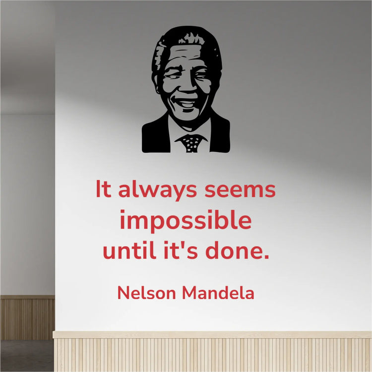 Red Nelson Mandela quote "It always seems impossible until it's done" wall decal in Modern font, placed next to a black silhouette image decal of Nelson Mandela, on a light-colored office hallway wall.