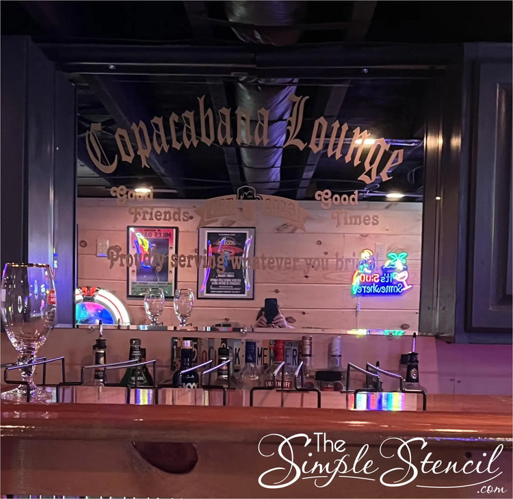 A personalized mirror decal adds a touch of whimsy and camaraderie to a home bar, proudly proclaiming the establishment's name, "Cococabana Lounge," as a haven for good friends and good times. The decal's jovial message, "Proudly serving whatever you bring!" sets a welcoming tone, inviting guests to bring their favorite beverages and enjoy the company of fellow revelers. Customize yours at The Simple Stencil