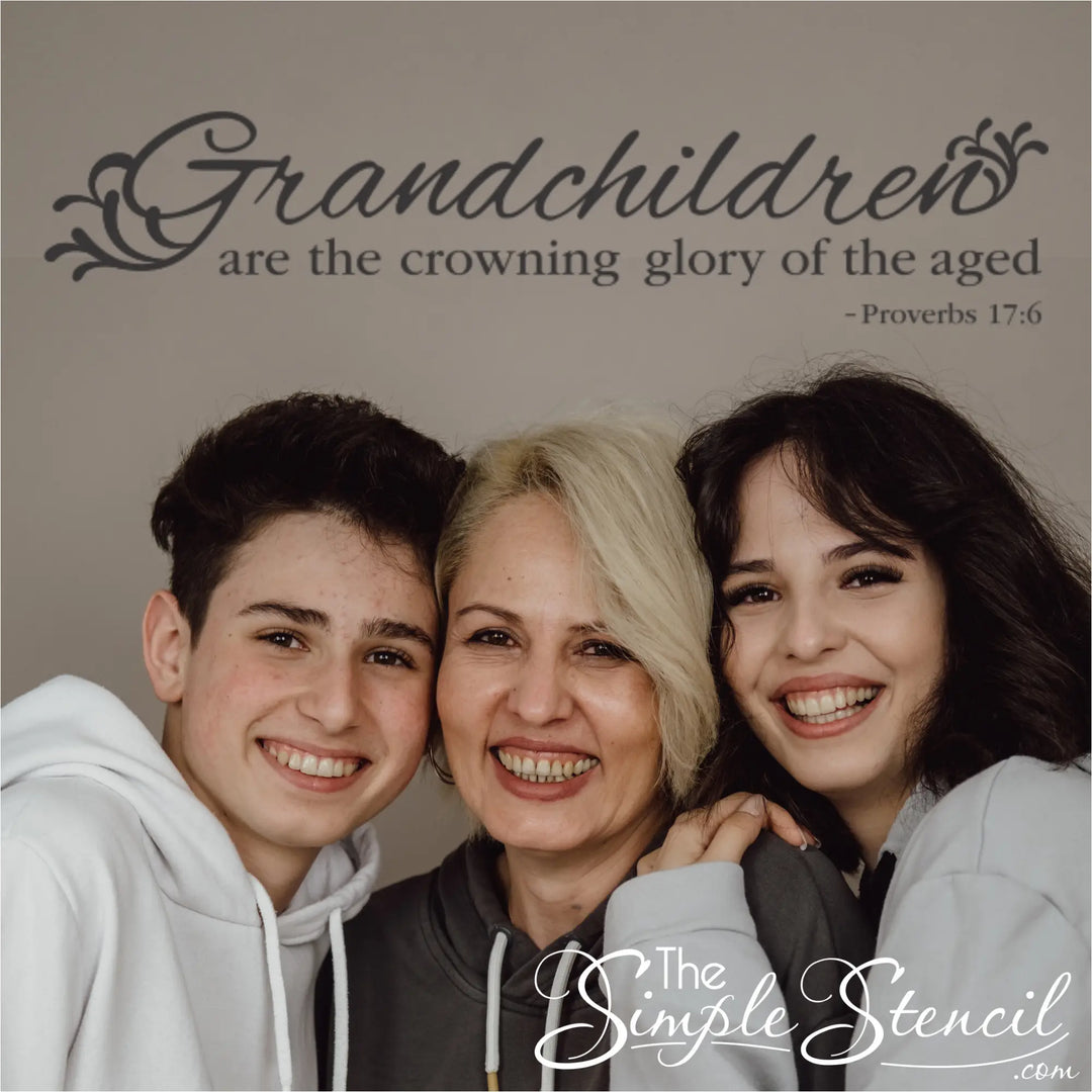 Matte charcoal grey Proverbs 17:6 wall lettering displayed on a neutral wall above a grandmother smiling with her two teenage grandchildren, perfect for a family gallery wall.