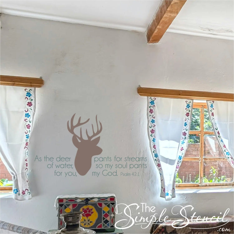 Brown Psalm 42:1 scripture decal displayed on a rustic white wall between two windows with floral curtains, perfect for a cozy cottage or lake house.