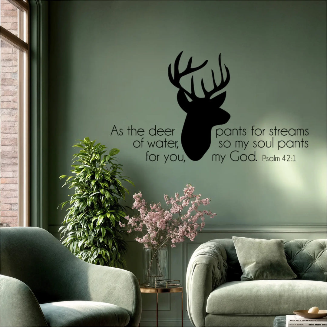Black Psalm 42:1 deer head wall decal on a modern sage green wall, styled above a velvet sofa with pink flowers, highlighting a sophisticated religious aesthetic.