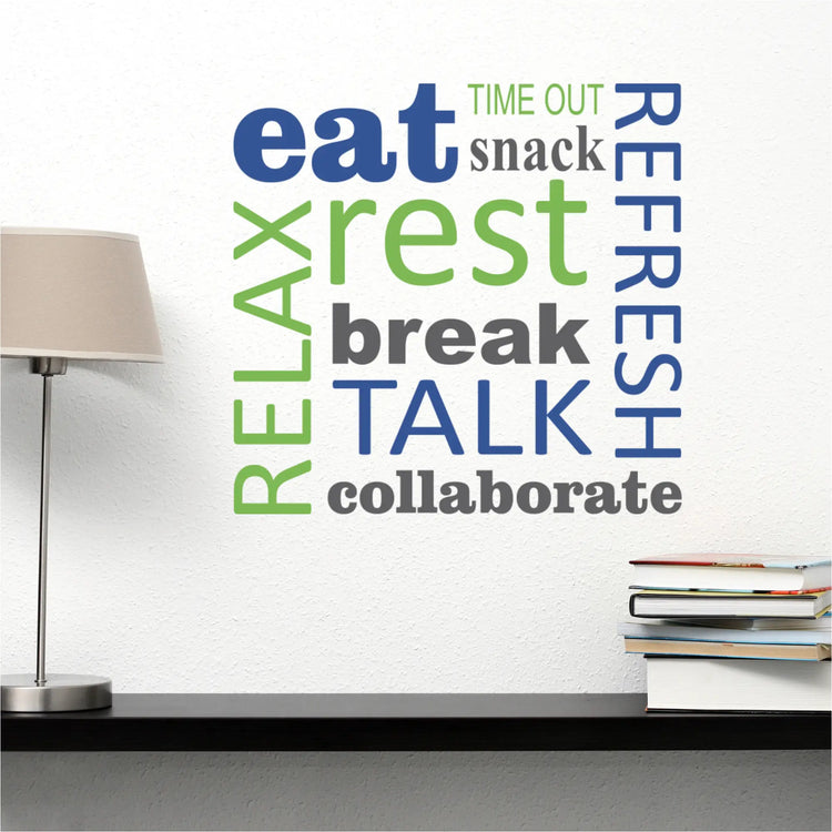 Motivational vinyl wall art with words like 'eat, rest, refresh, relax, talk, collaborate' in blue, green, and grey, installed on a beige wall in a comfortable lounge or living space. A floor lamp creates a light and cozy atmosphere.
