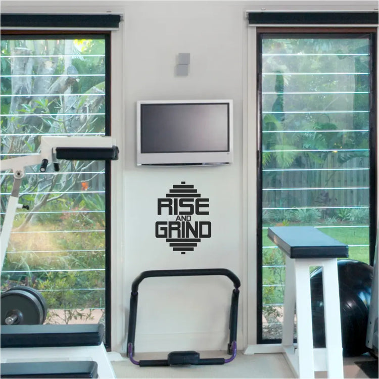 RISE AND GRIND Gym Wall Decal displayed prominently in a home gym, inspiring a workout.