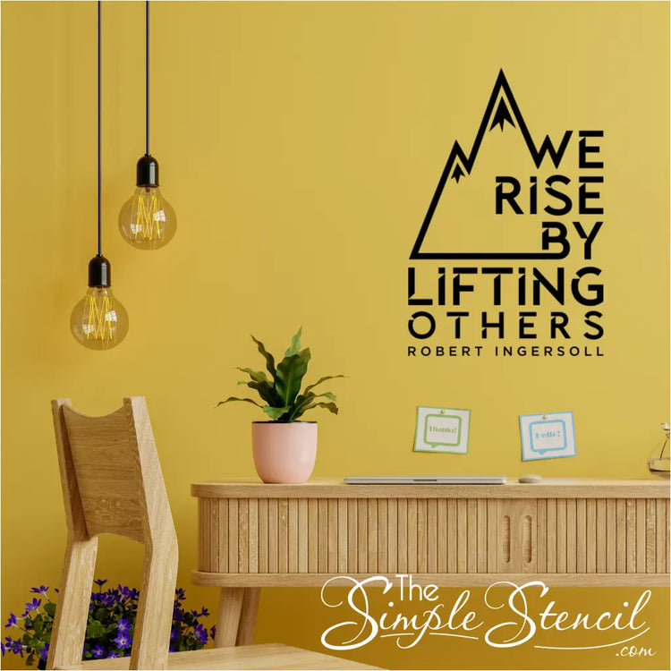 Wall decal with the quote "We rise by lifting others" and a mountain design.